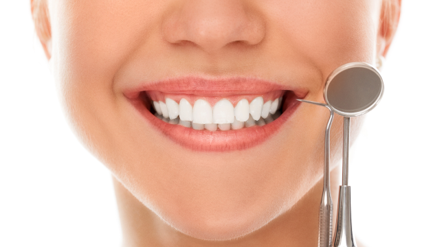 Smiling patient with a full set of fixed teeth and a dental mirror