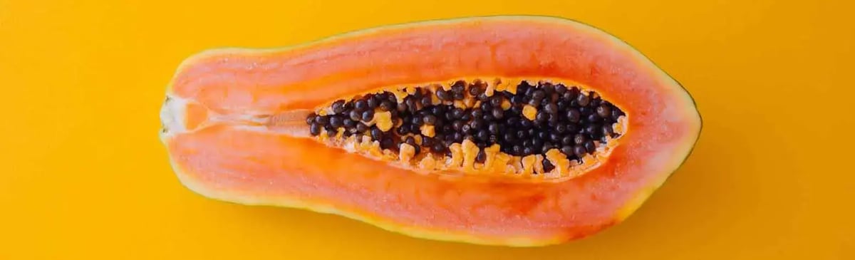 Halved papaya on a yellow background - a discreet symbol for labiaplasty