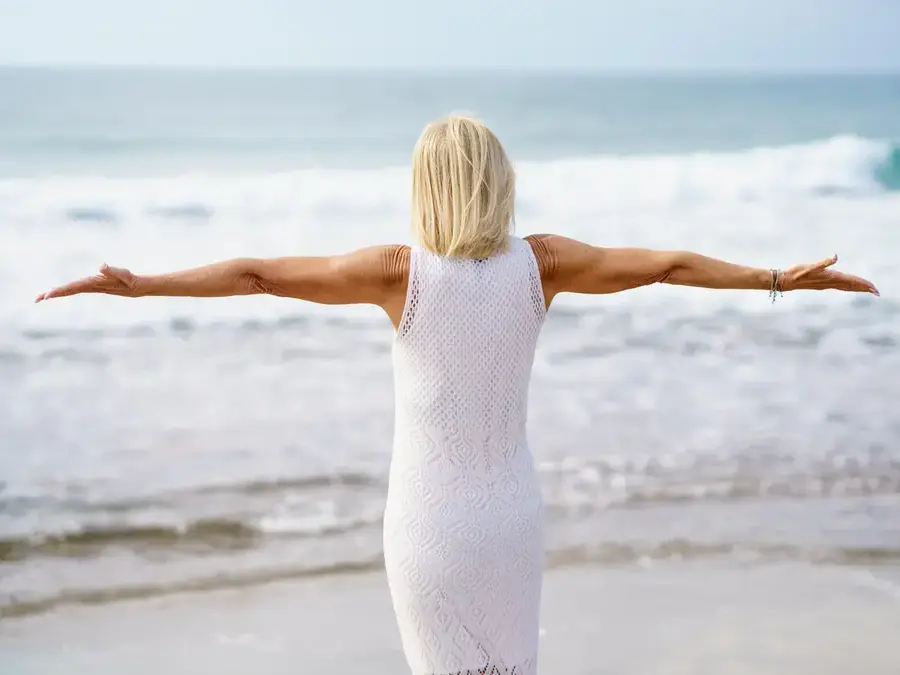 Stock photo: woman in a white summer dress with open arms by the sea