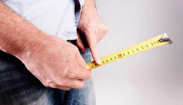 Man in jeans holding a tape measure - a discreet symbol for penis enlargement